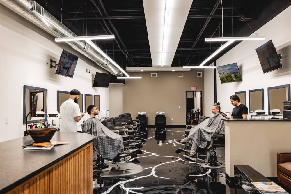Two males cutting hair in a barbershop.