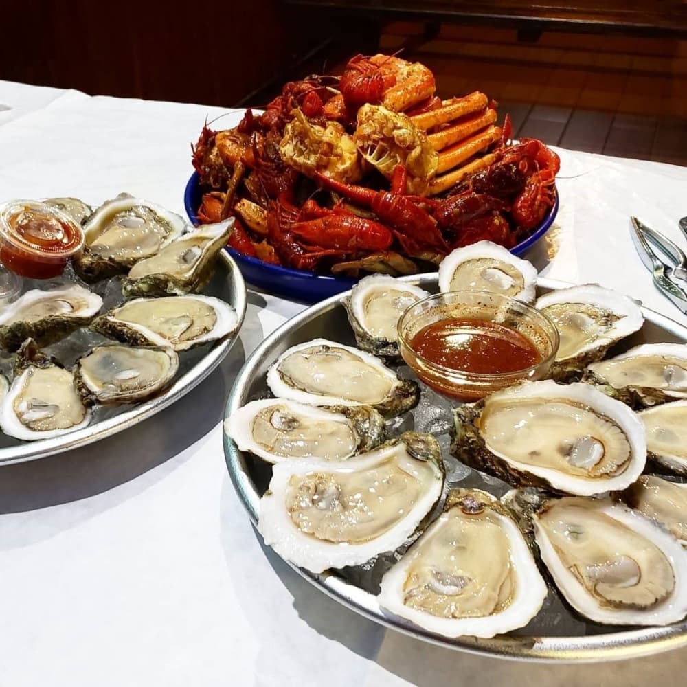 A table is filled with clams on the half shell and boiled seafood.
