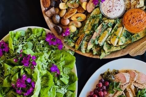 Three plates with salad, roasted vegetables and sliced meat. 