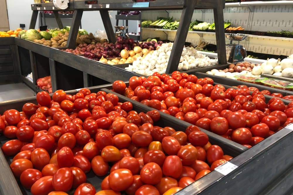 Bins filled with tomatoes and other vegetables in a store. 