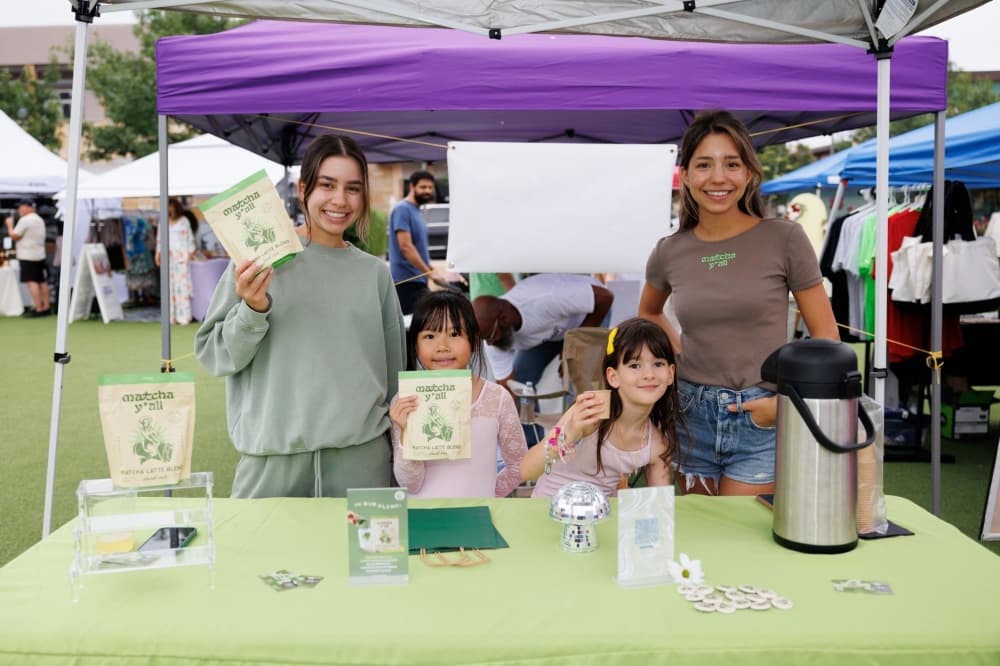 A photo of a booth with its hosts posing for a photo. 