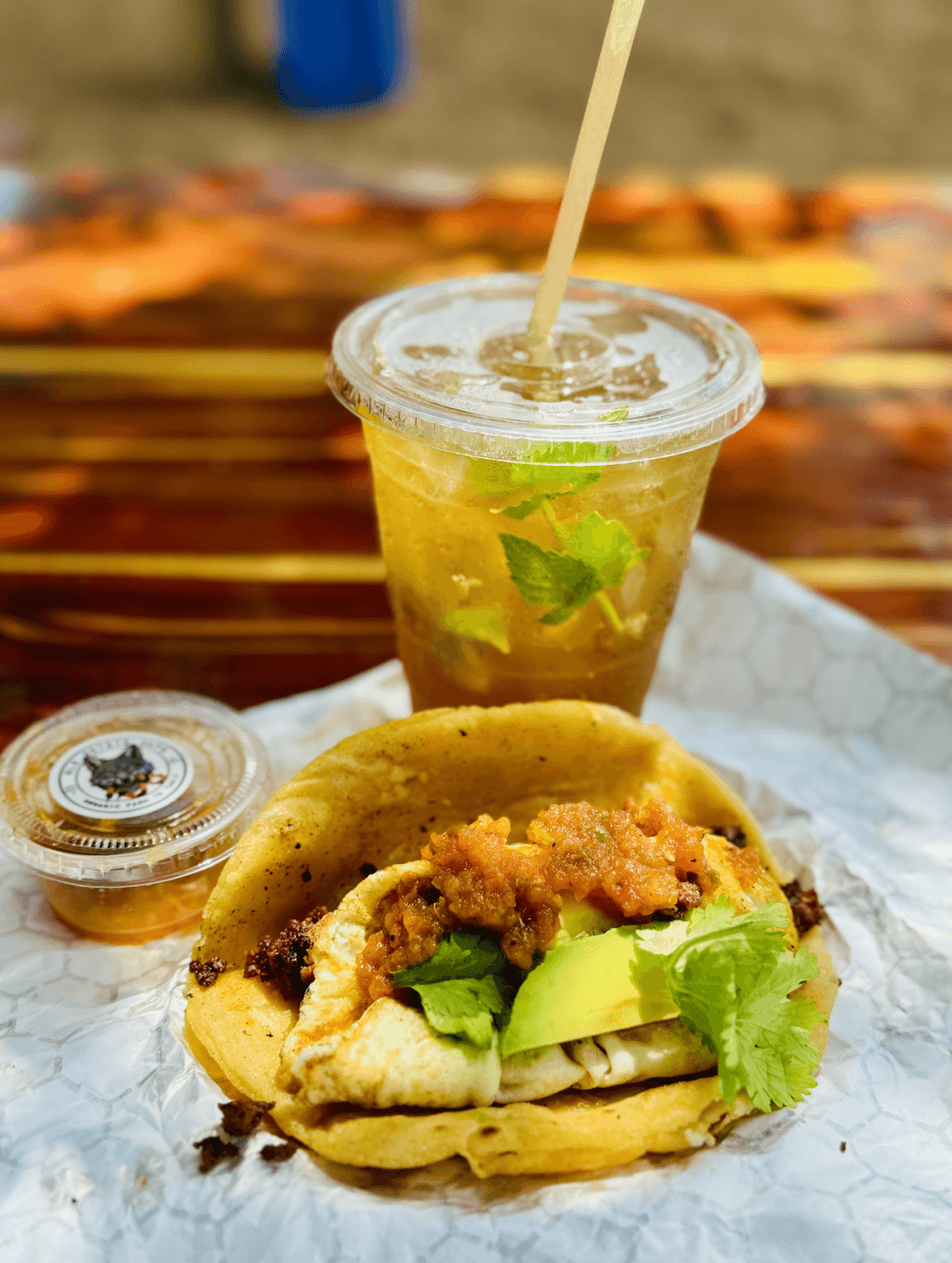 A taco, drink and sauce.