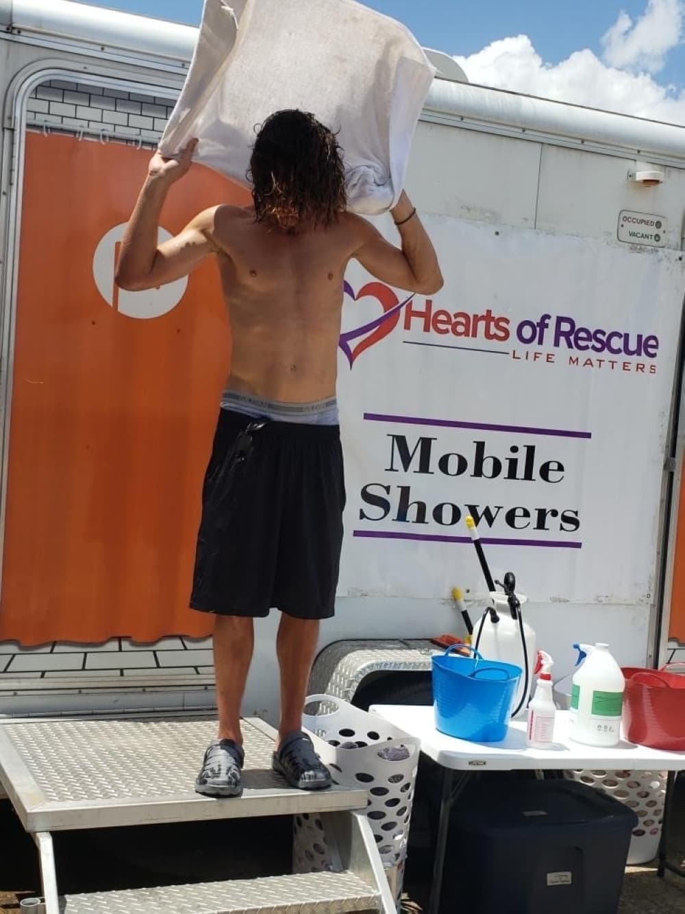 Man drying himself with a towel after taking a Hearts of Rescue shower.