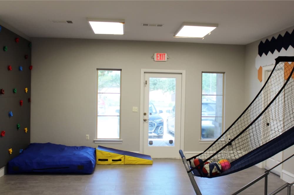 Room with rock wall and basketball game. 