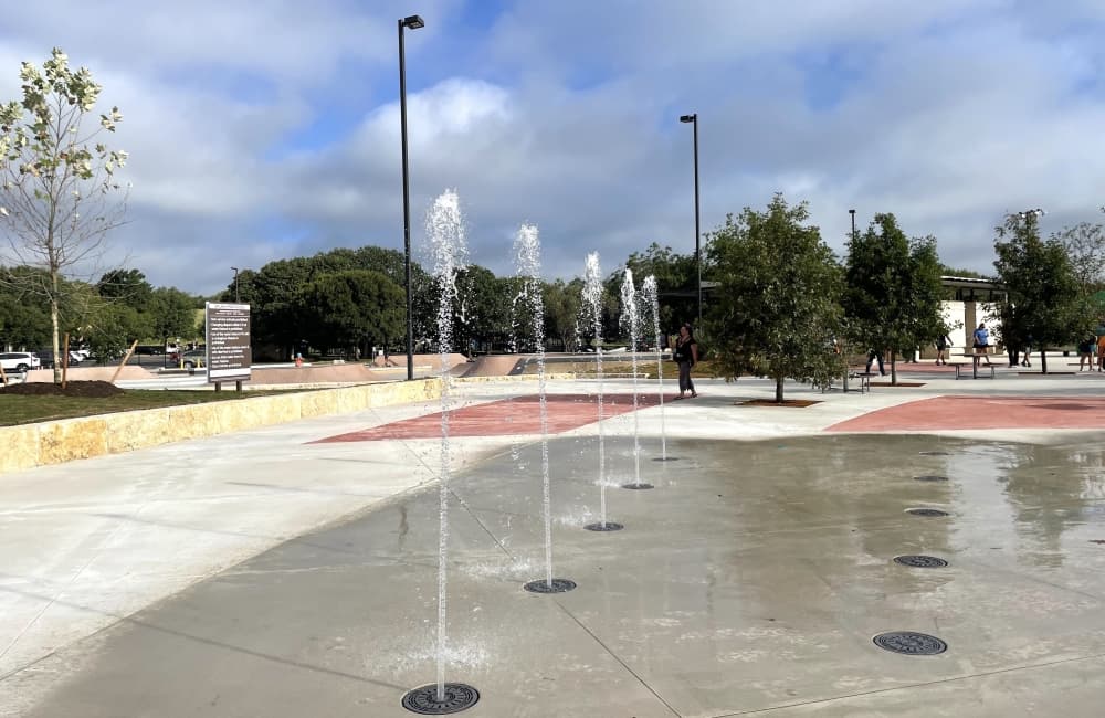 A splash pad sprays water at an outdoor park 