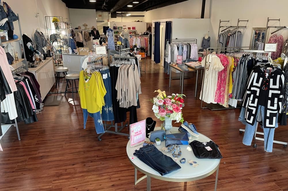 Interior of a store with clothing displayed on racks and a table. 