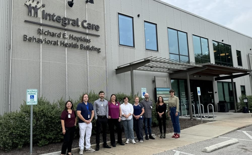 The Integral Care team stands outside the Richard E. Hopkins Behavioral Health Building. 