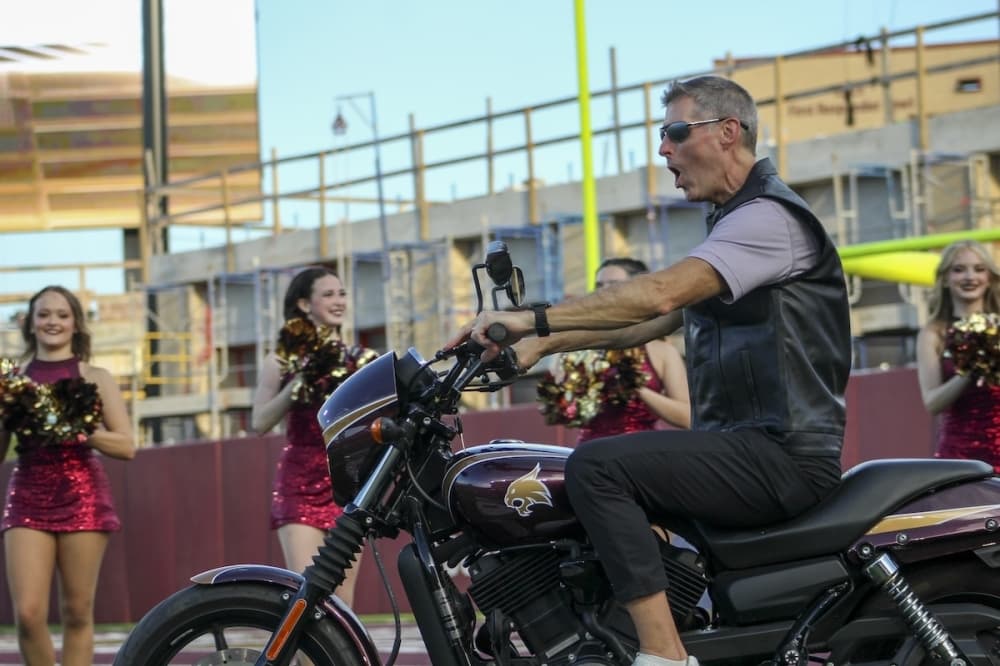 UFCU CEO and President Michael Crowl riding a motorcycle onto the field