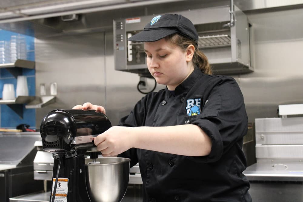 A high school student mixing cookie dough. 