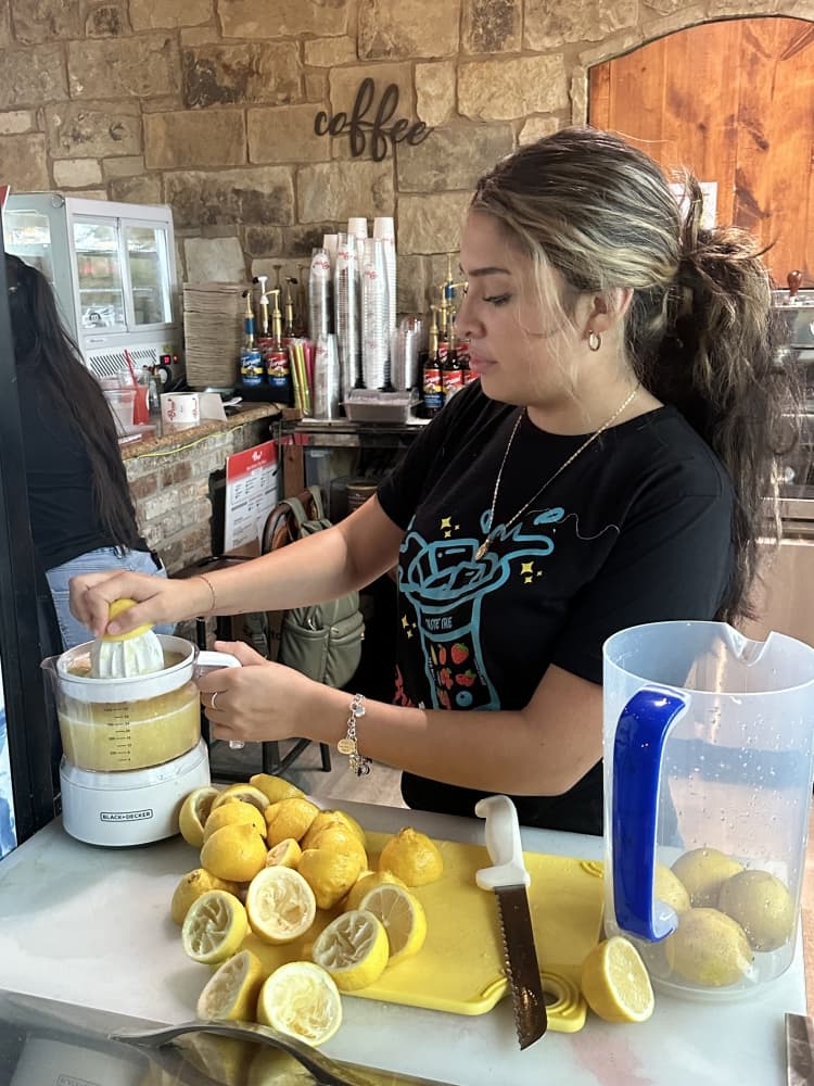 A barista squeezes lemons for the juice.