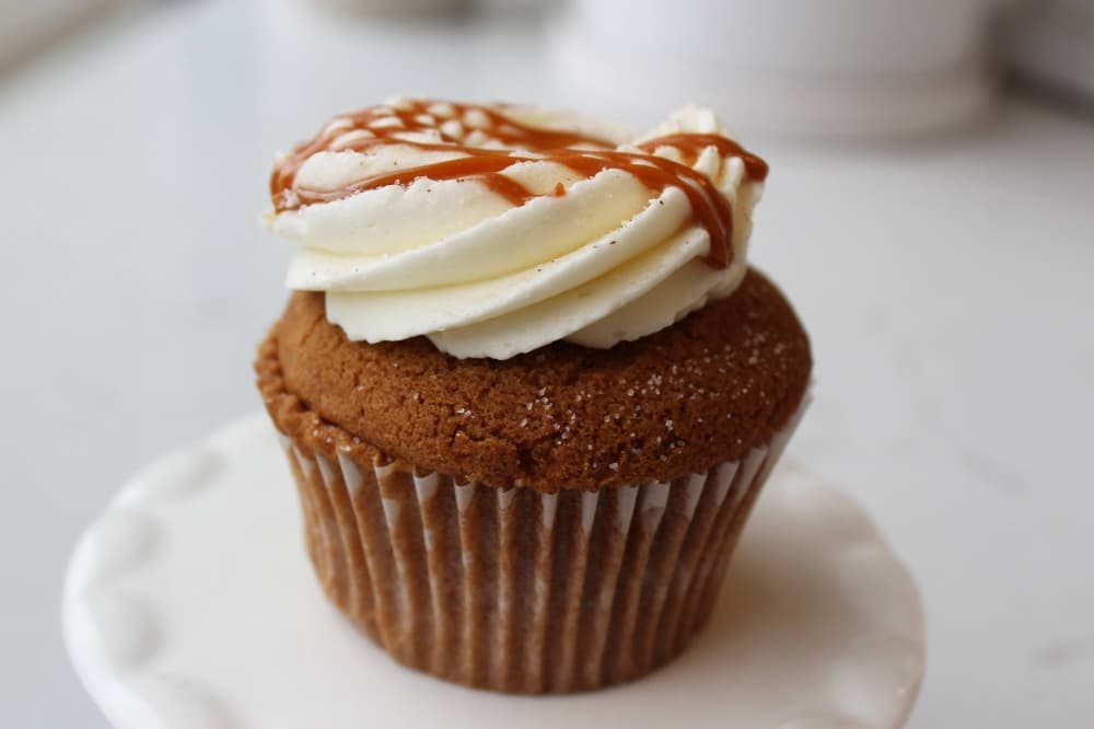 Brown cupcake with off-white icing and brown drizzle. 