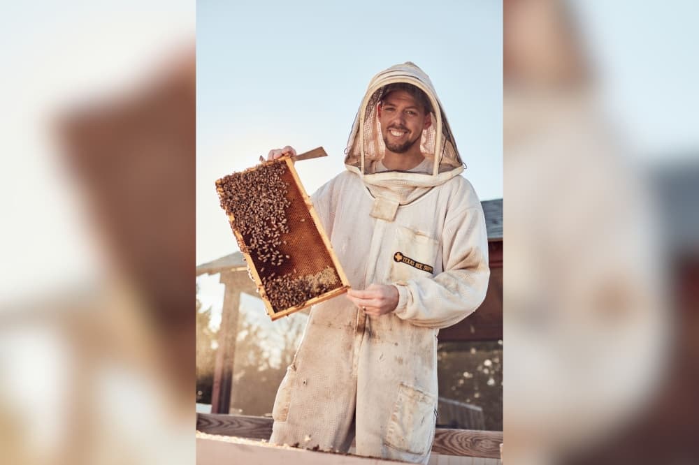An image of founder Blake Shook with a beehive. 