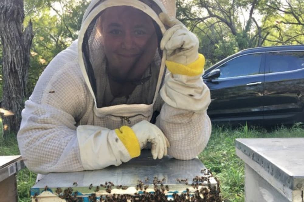 An image of Store Manager Becky Barajas with a beehive. 