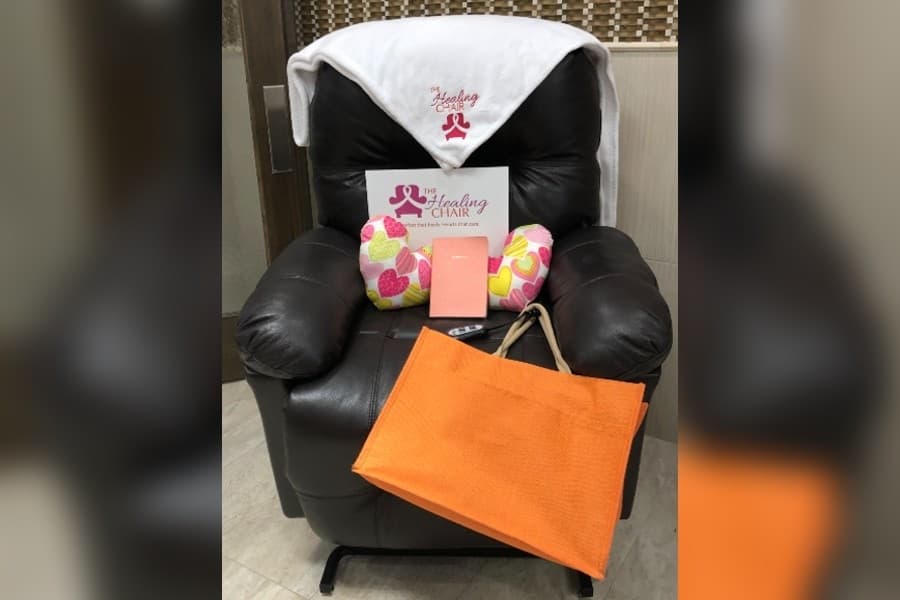 Leather recliner chair with The Healing Chair branded blanket, pillows, journal and bag. 