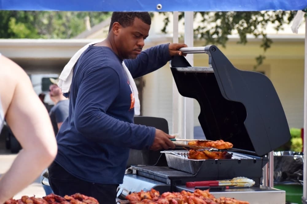 man cooking chicken on a grill