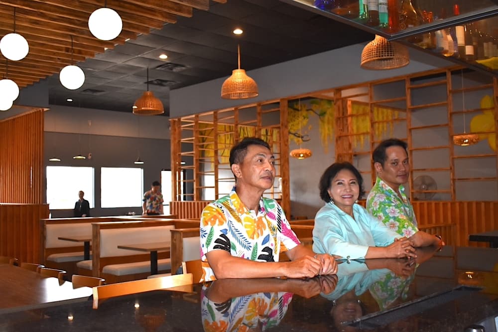 Three people sit at a counter in a restaurant