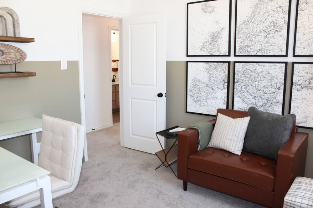 Carpeted room with framed maps on the wall and two chairs and a table. 