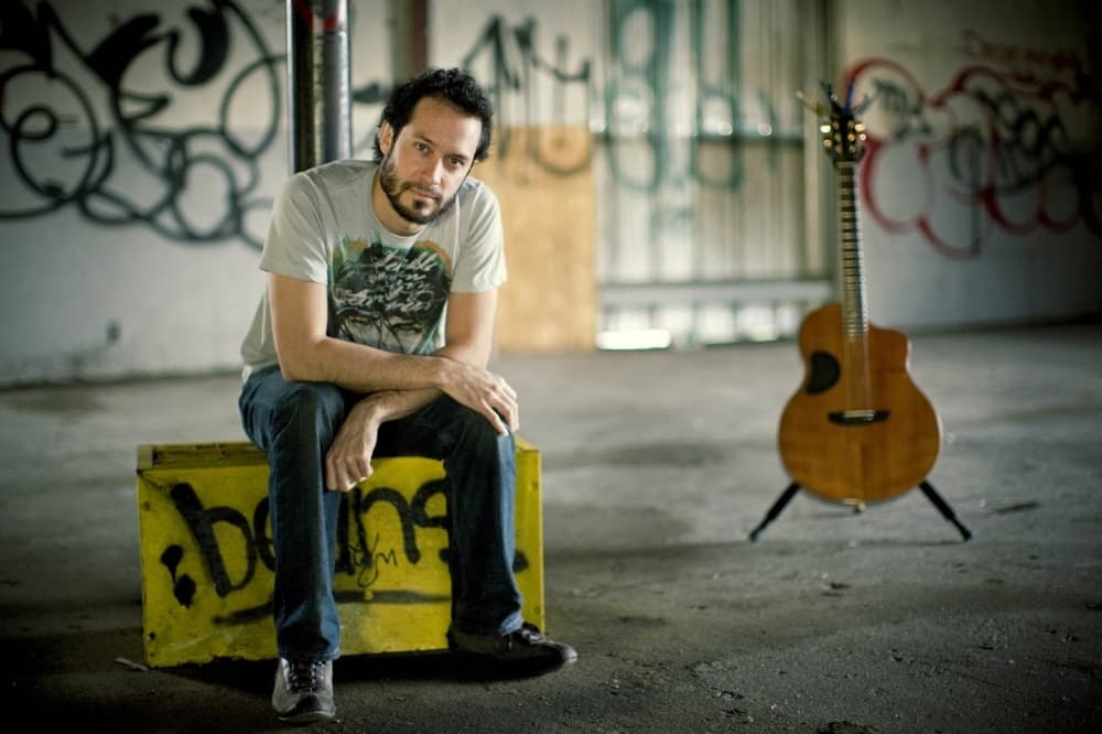 Trace Bundy sitting down with his guitar in the background. 