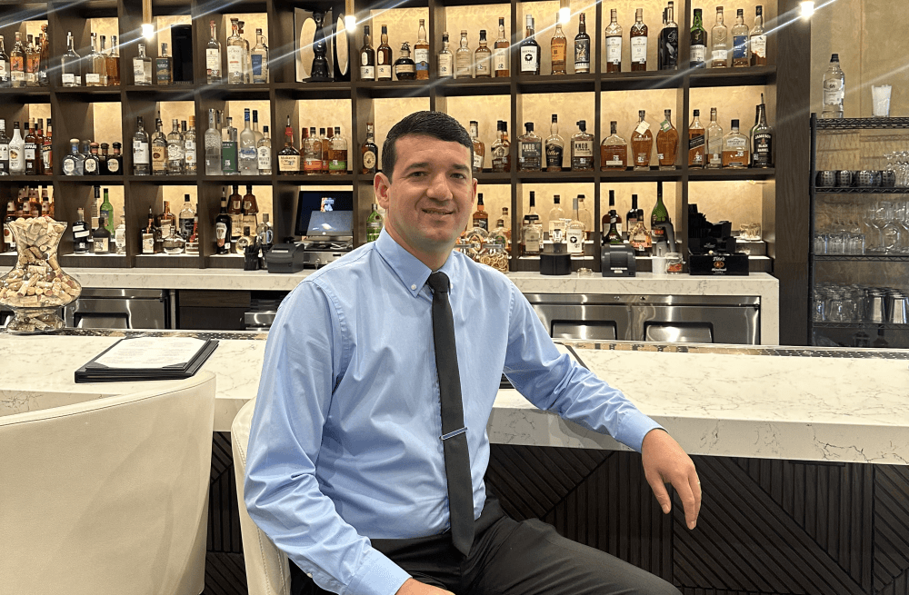 Restaurant manager Paulo Serafini smiles for a photo by the Chama Gaucha restaurant's full bar. 