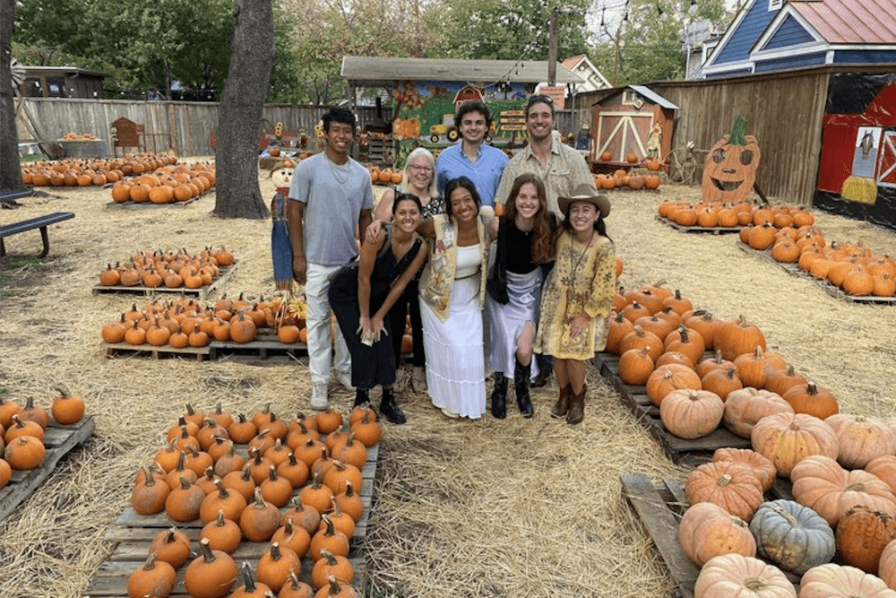 People pose while standing in a pumpkin patch.