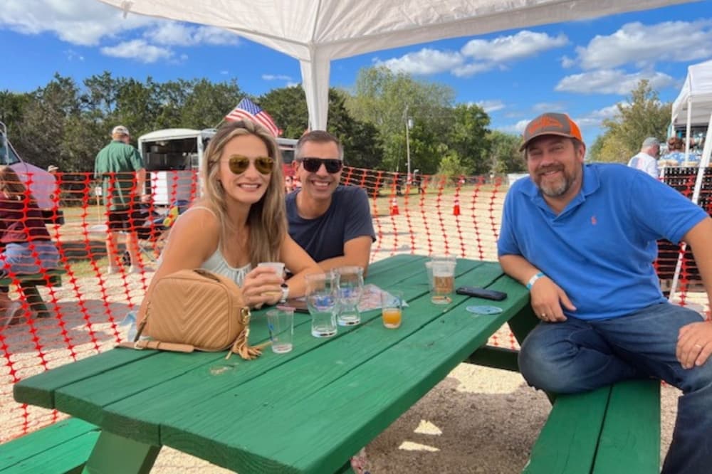 An image of three participants sitting at a picnic table at a previous beer festival. 
