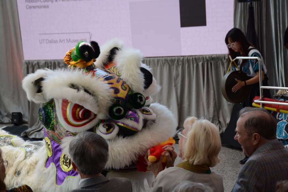 An individual at the ribbon cutting ceremony for the Athenaeum receives a special gift during an Asian visual art performance. 
