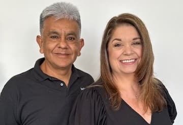A husband and wife pose for a photo. 