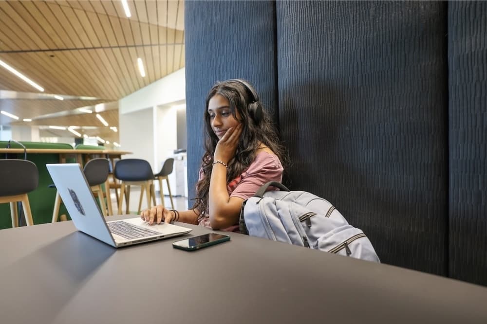a girl looks at her laptop in a university work space