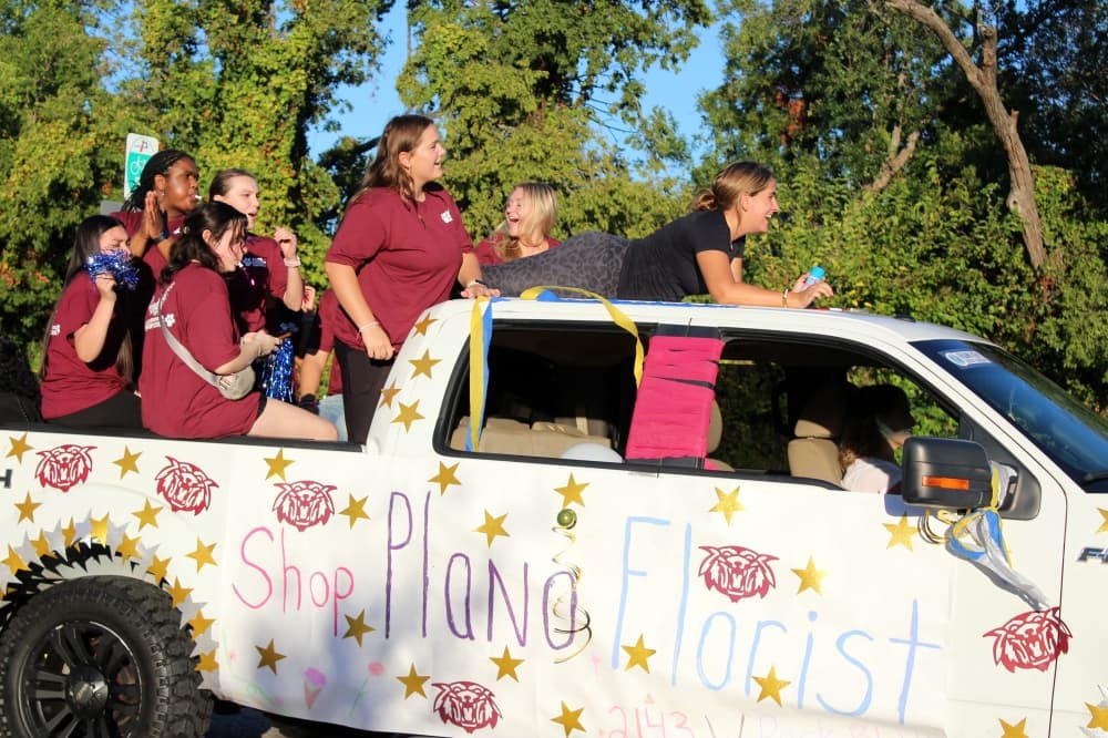 Teens in a truck bed in a parade. 