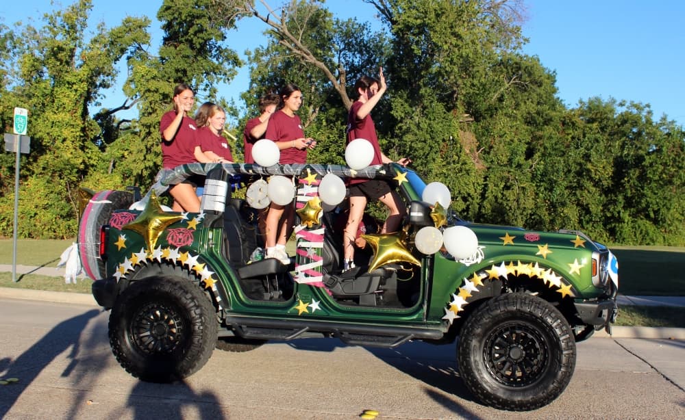 Teens in a jeep in a parade. 