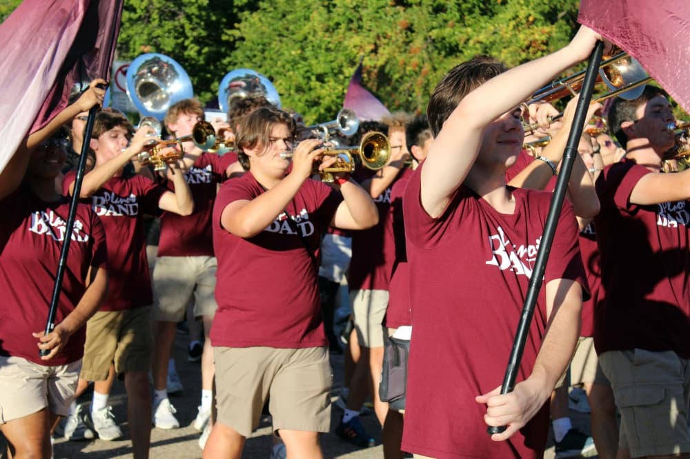 Band members and color guard marching in a parade.