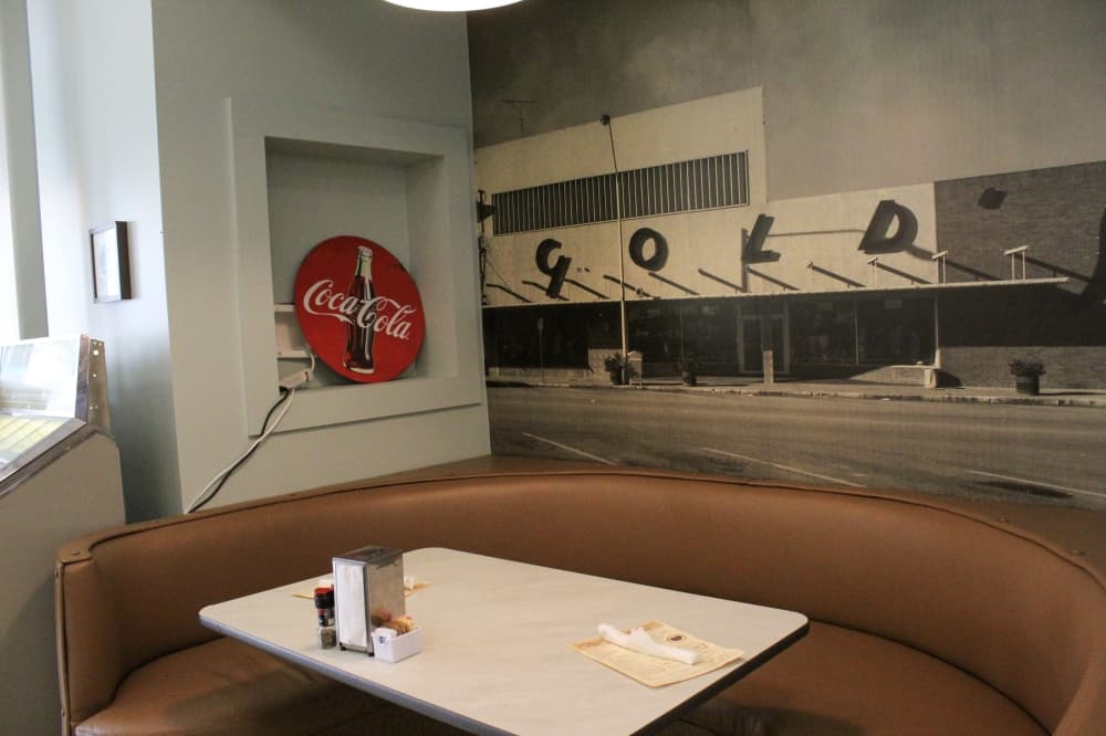 An image of a booth inside the restaurant with a picture of the Gold's Department Store above it. 