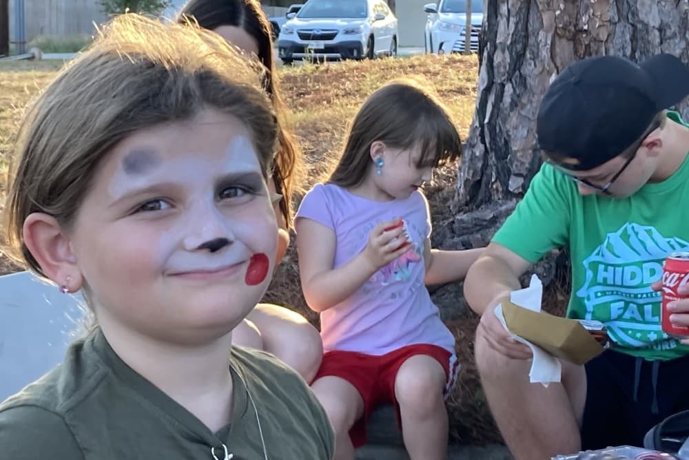 A child with facepaint is in the foreground.