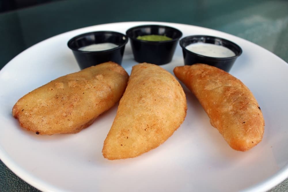 Three empanadas with three different dipping sauces. 