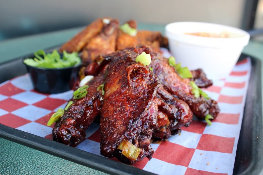 Two stacks of seasoned wings on a tray with a red/white checkered tray cover. 