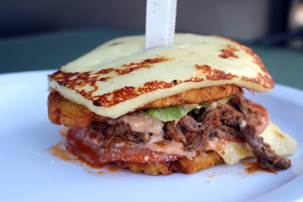 Sandwich with cheese, brisket, plantains and sauce. 