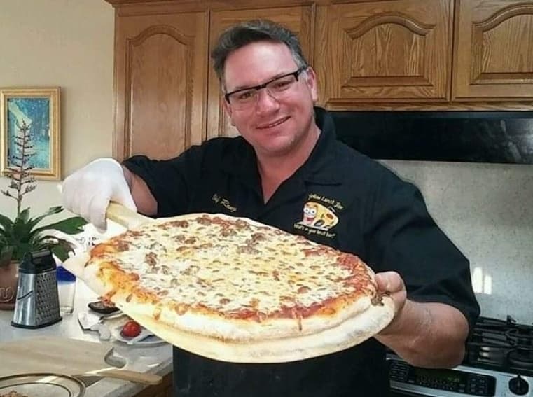 Ron proudly presents a pizza creation for his family while in the initial stages of operating a food truck. 