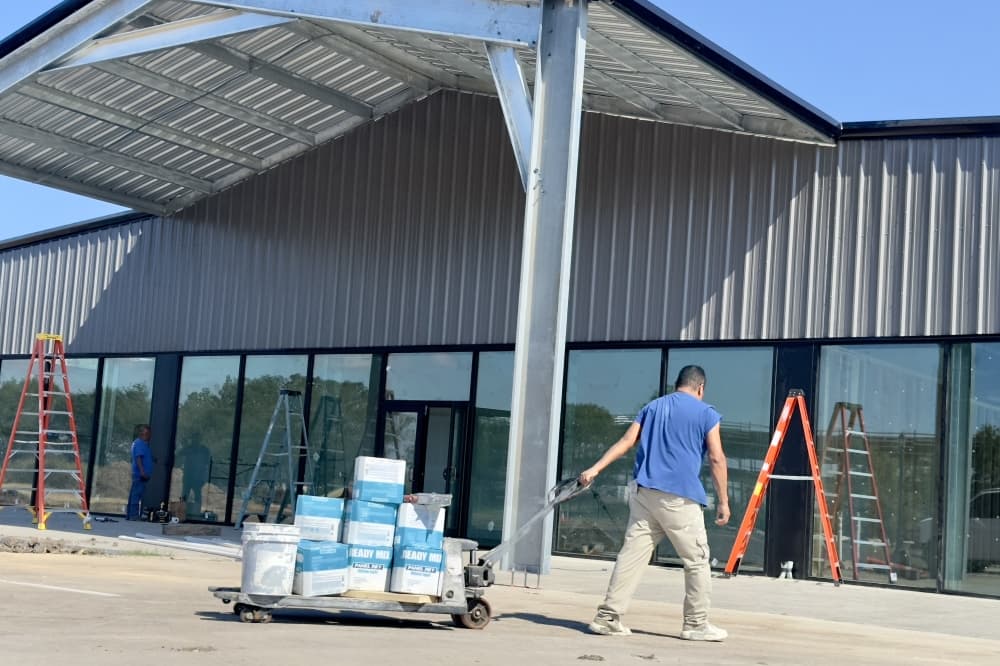 A worker pulls a pallet with construction supplies in front of the building.