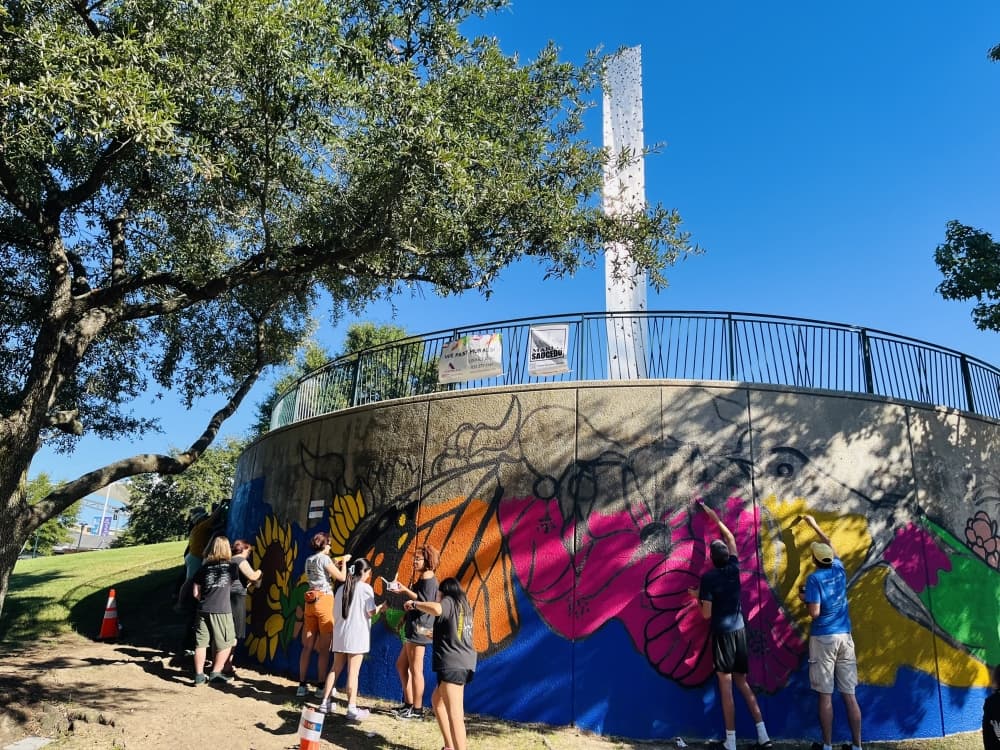 People work on a mural outdoors