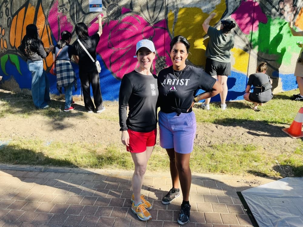 Two people stand by a mural in progress
