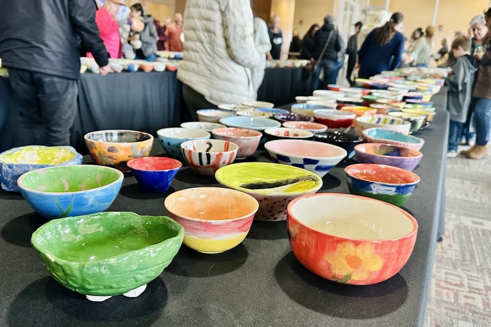 A table is filled with hand-painted bowls from the previous Bastrop Empty Bowl event.