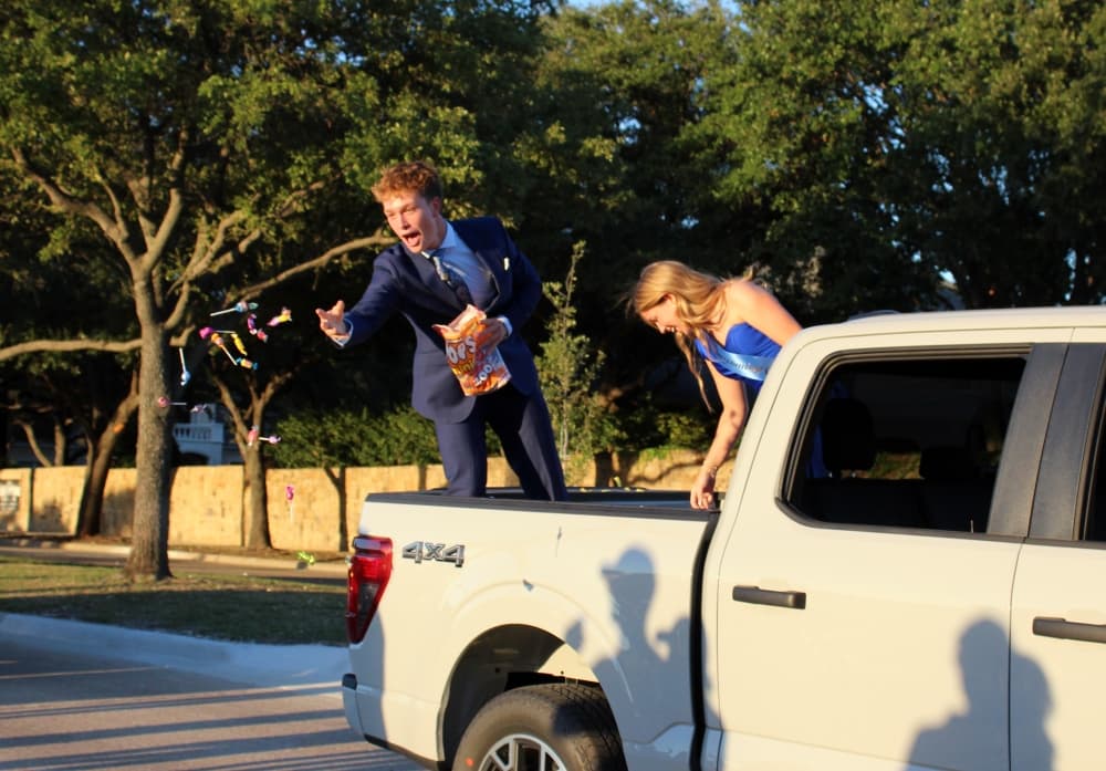 Male tossing candy from the back of a truck in a parade. 