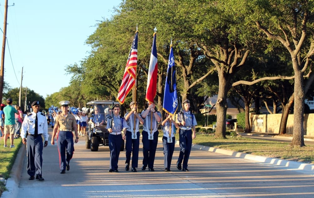 ROTC members carrying flags while leading a parade. 