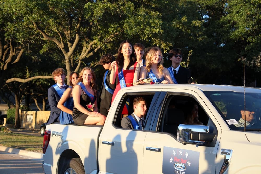 Students riding in the back of a truck in a parade. 