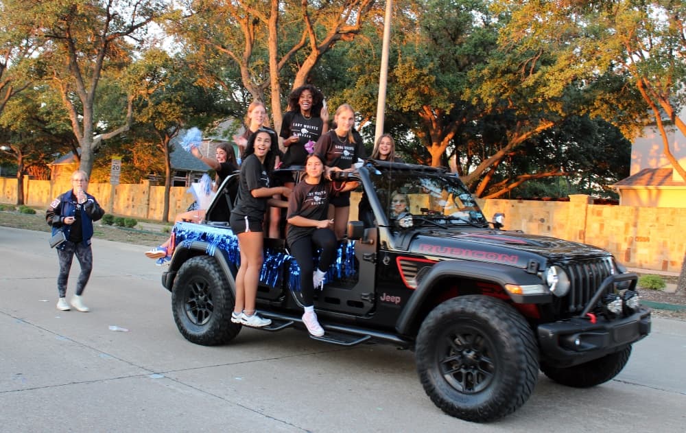 Students riding in a jeep in a parade. 