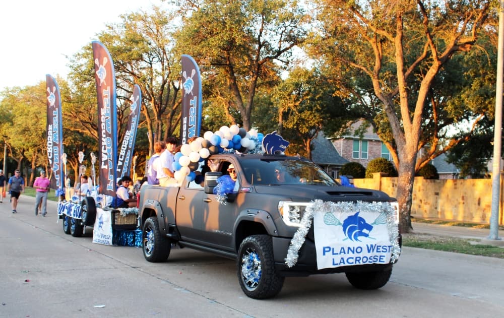 Decorated truck towing flatbed trailer with students in it in a parade. 