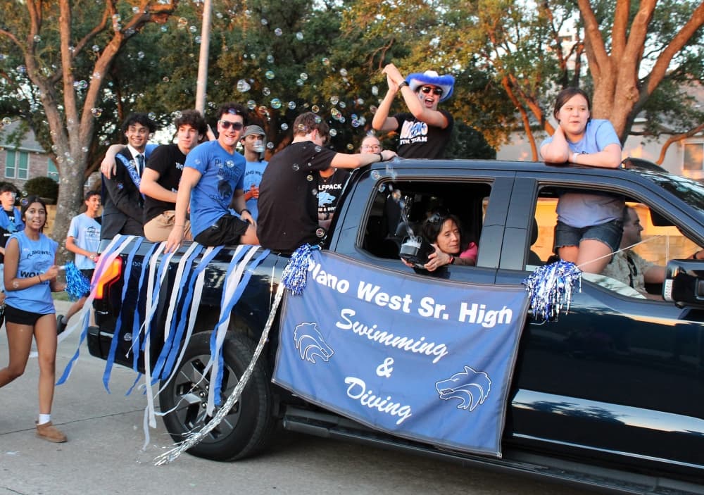 Students riding in the back of a white truck in a parade. 
