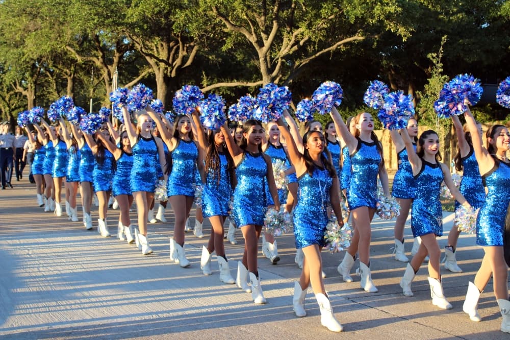 Drill team marching and lifting pompoms in a parade. 
