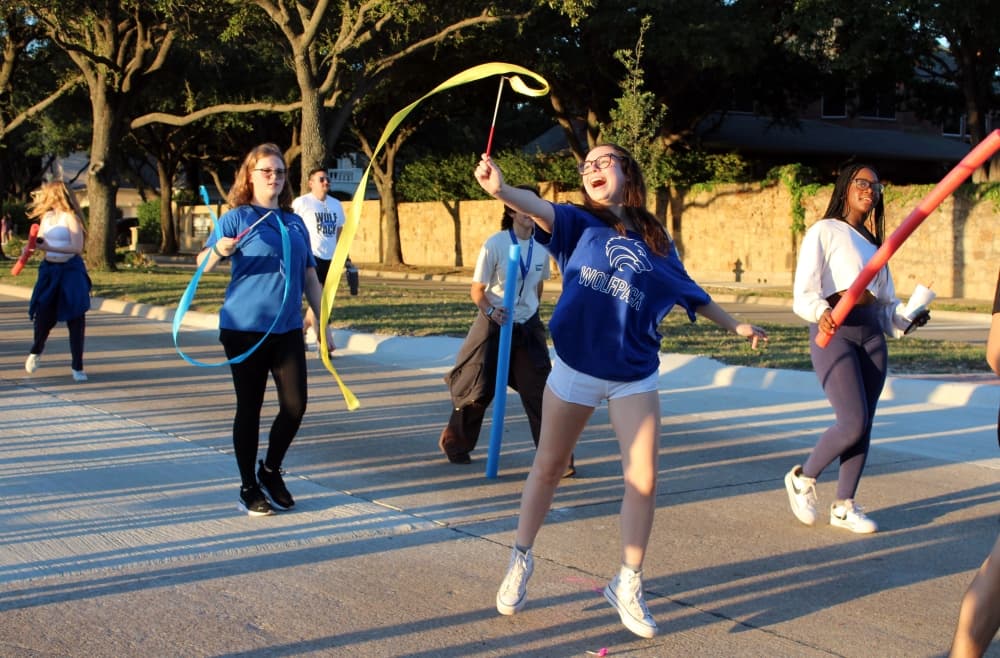 Students in a parade twirling flags.