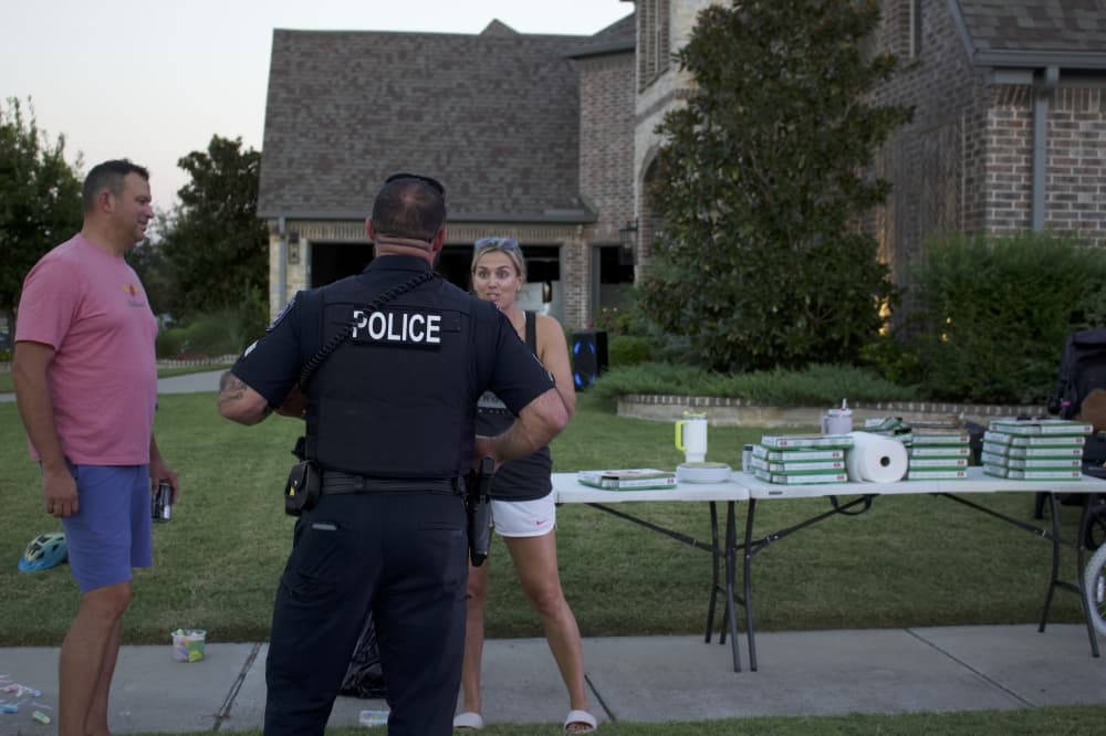 A Prosper police officer stands with residents at an Oct. 1 block party for National Night Out. (Alex Reece/Community Impact)